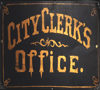 Antique sign with a black background and gold lettering that reads: "City Clerk