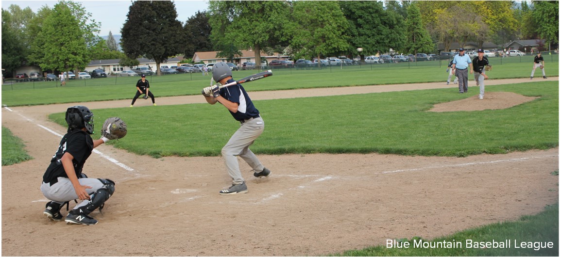 Teenagers play baseball on a baseball field