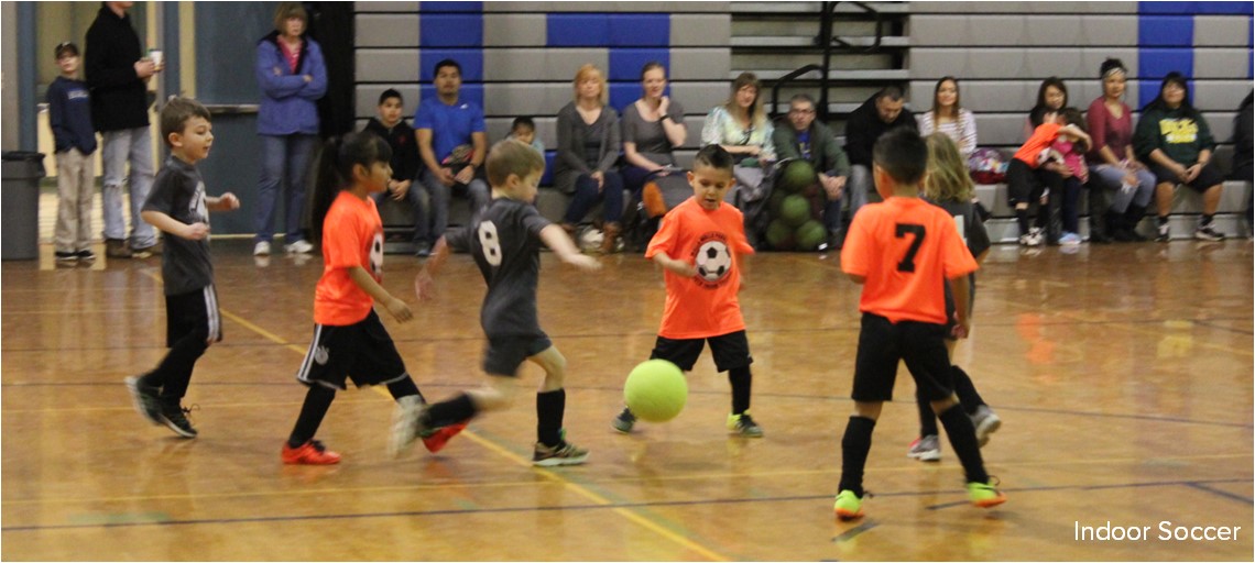 Children play soccer in a gymnasium