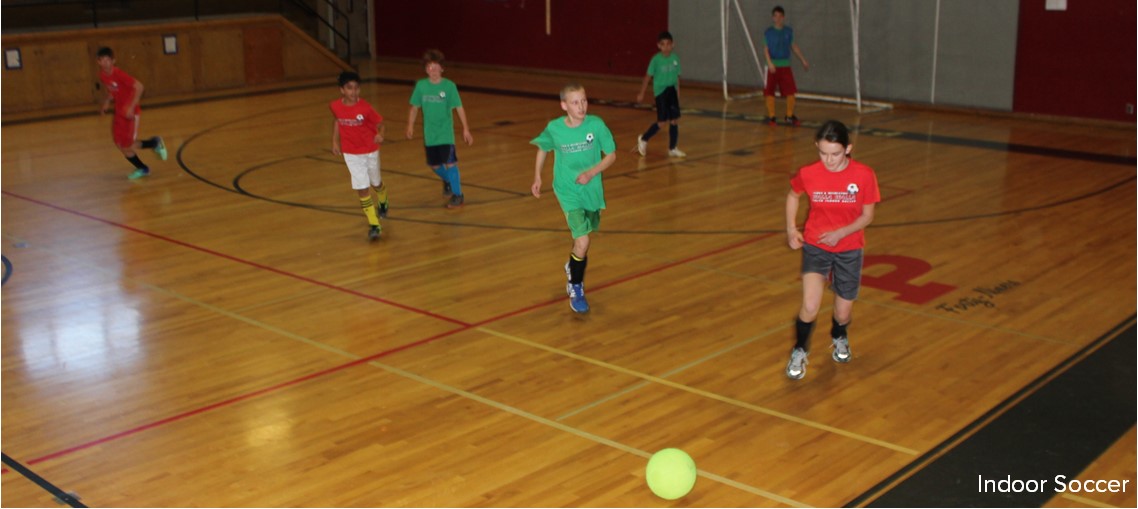 Children play soccer in a gymnasium