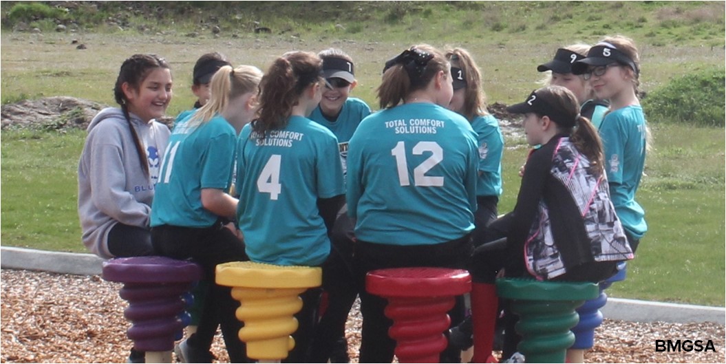 Members of a softball team sit in a circle and talk together