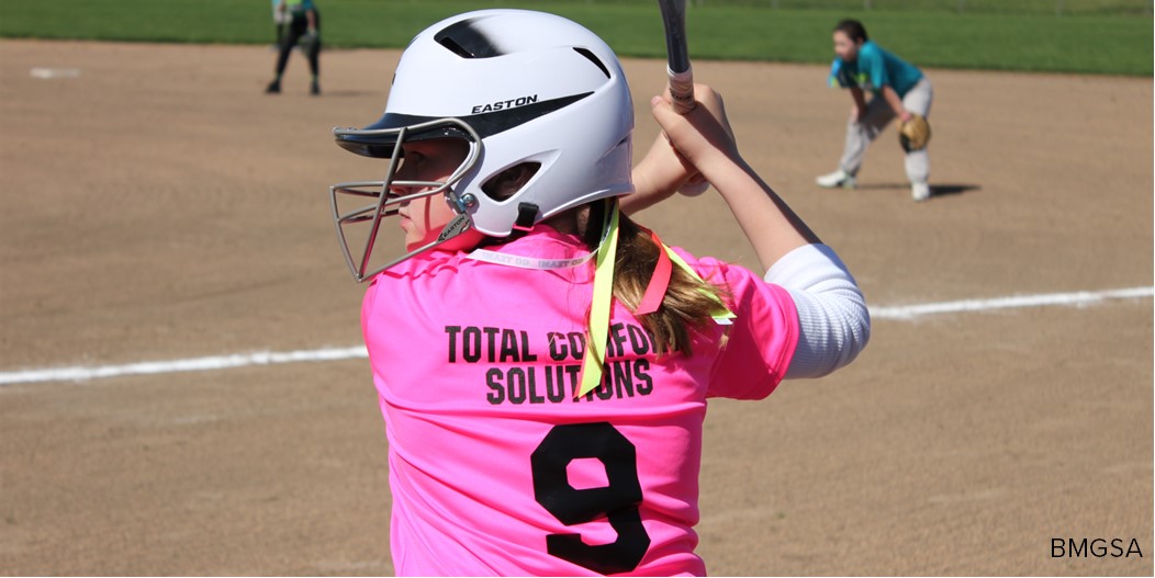 An on-deck softball player warms up with a bat