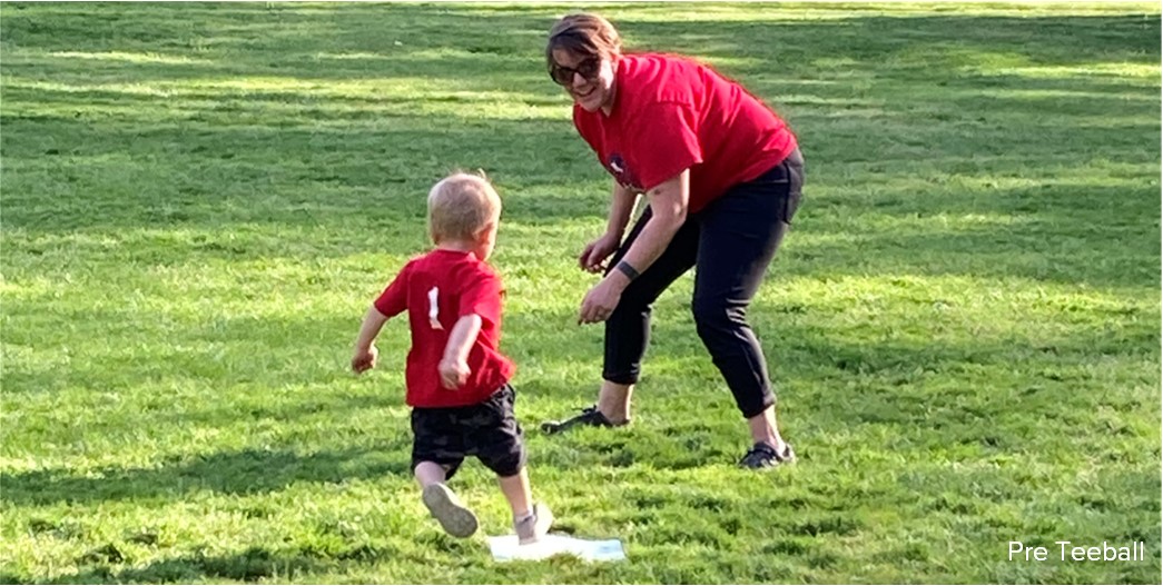 An adult coaches a young child on how to run the bases on a baseball diamond