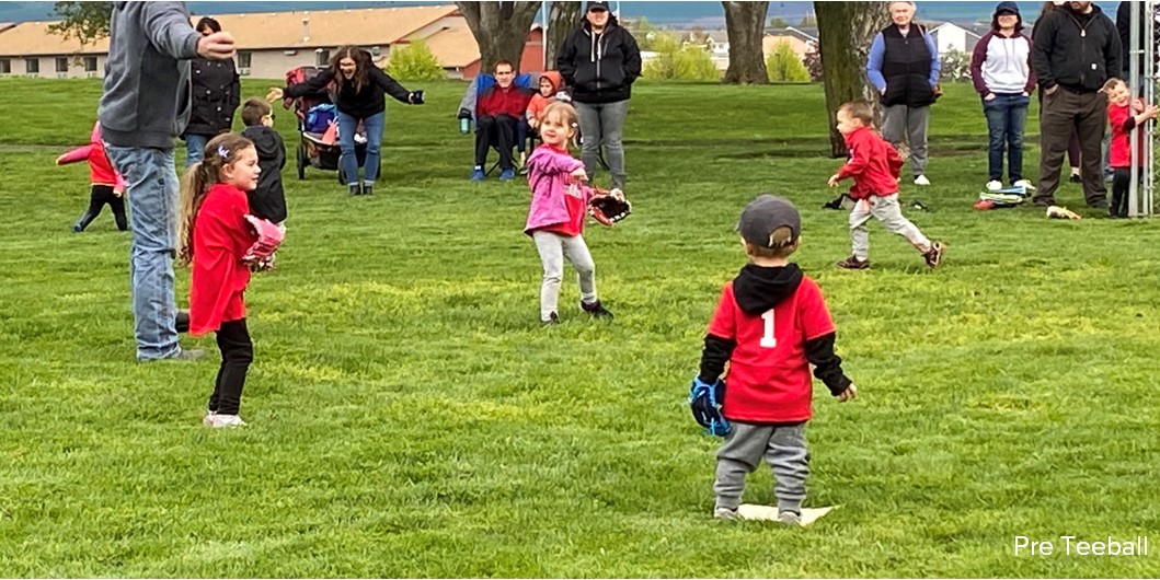 Young children practice throwing a baseball and catching it in their baseball gloves