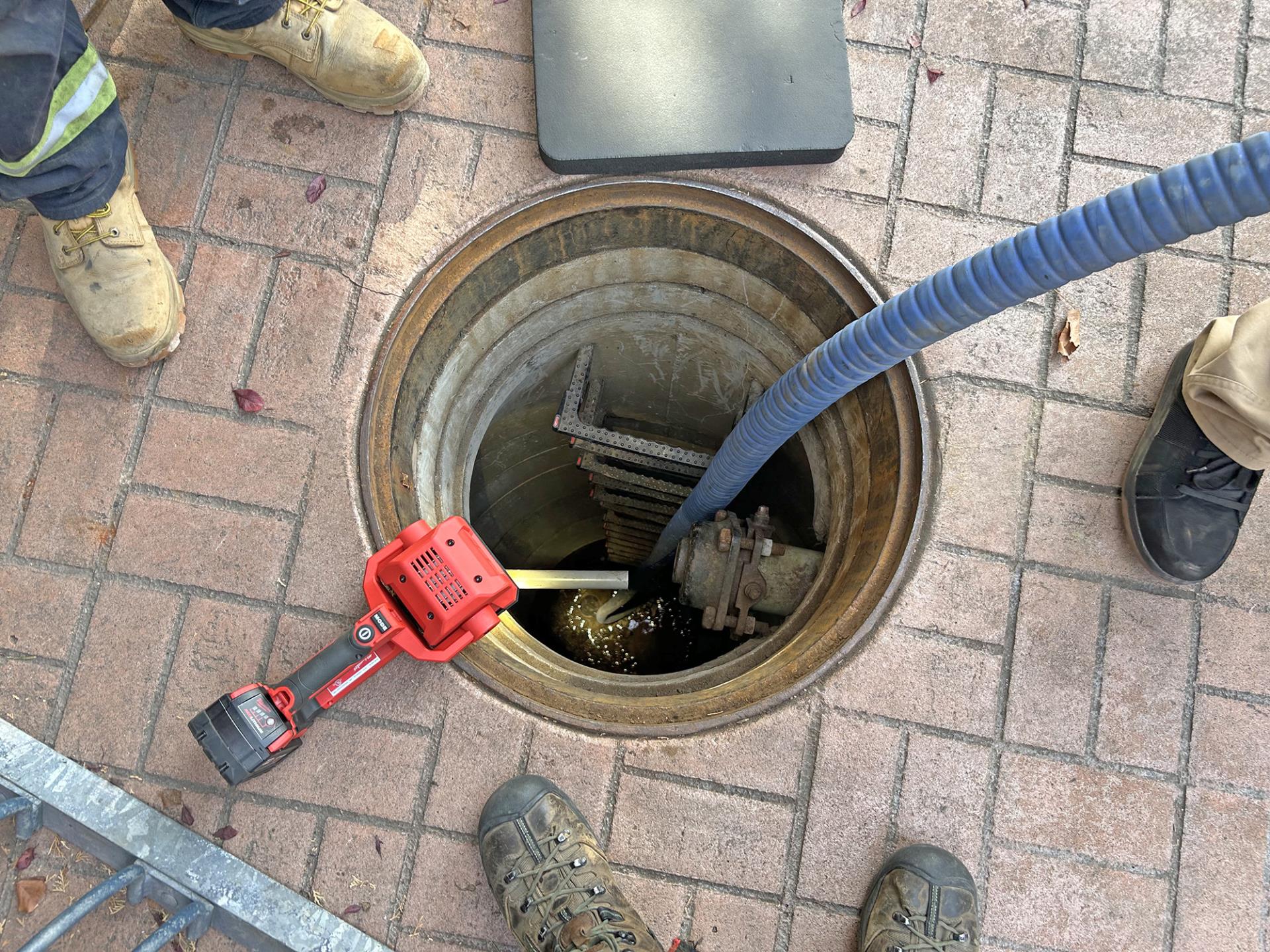 The exterior groundwater sump adjacent the Marcus Whitman Hotel is pumped to remove water with visible sheen.